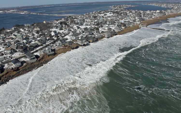 NEWBURY, MA - MARCH 9: Waves pound against Plum Island, a narrow strip of land, eroding the shoreline. The two homes that fell off their foundations after being damaged in yesterday's winter storm can be seen in this aerial view. (Photo by David L. Ryan/The Boston Globe via Getty Images)