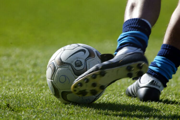 A footballer kicking a football.